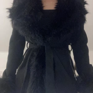 Svart kappa med fuskpäls  - En svart kappa med fuskpäls som håller värmen bra. Den är i storleken xs och är använd ett antal gånger men är fortfarande i bra skick. Ordinarie pris i butik är 1000kr 