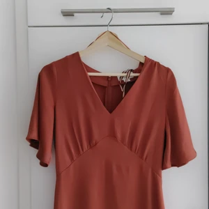 Rostfärgad klänning  - Jättefin klänning från Lindex. Använd endast en gång på dop. Det har gått en liten maska men den syns knappt. Skicka meddelande för fler bilder.  Storlek 36 men passar också en mindre 38. 