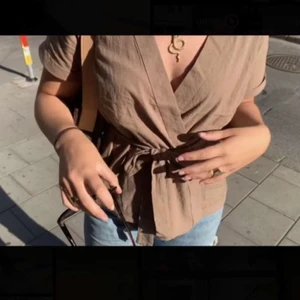 Blus i linne - Säljer denna beige/bruna linneblusen från Nakd. Har endast använt den ett fåtal gånger så den är i fint skick. Skulle säga att tröja passar både mindre och större eftersom du själv knyter den i midjan. Kan mötas upp i Stockholm eller frakta men köparen står för frakten. Superfin till sommaren