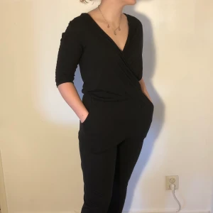 Svart byxdress - Supersnygg svart byxdress med fickor (!!!) och djup urringning. Bra skick! Från Bik Bok