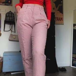 Gingham kostymbyxor - Figursydda rosa byxor med gingham-mönster. Materialet är runt och luftigt och passar perfekt till sommaren. Byxorna är veckade längst upptill vilket ger dem en supersnygg figur och har fickor fram och fake fickor baktill. Tyvärr aldrig fått tillfälle att använda dem och garderoben är överfull så dem letar nu ett nytt hem. Stl. M