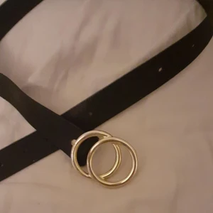 Skärp  - Ett svart skärp me guld ringar längst fram, köparen står för frakten