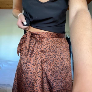 Kjol - Säljer denna jätte fina omlott kjolen från Neo Noir, i ett leopard liknande mönster i en jätte fin rostig färg🔥🔥 köpt för 499 kr i storlek S Men kan passa vem som helst så man knyter den själv hur hårt man vill att den ska sitta i midjan💞🧡🧡