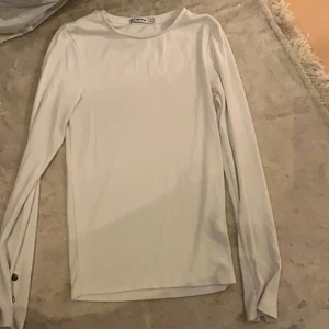 Storlek S - Jättefin basic tröja i vit färg med slits armar som går åt att knäppa till. 