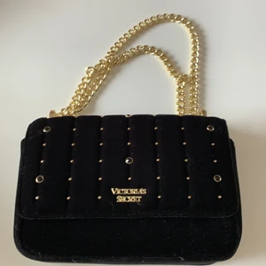 Victorias Secret väska - Svart väska i sammet från Victoria’s Secret. Axelbandet går att justera så man kan ha det kortare (typ i midjehöjd) och längre (typ rumphöjd). Väskan har ett innerfack och ett fack på baksidan. Väskan är aldrig använd. Köparen står för frakten🌸