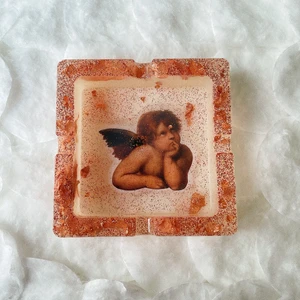 Hemmagjord askkopp - Hemmagjord askkopp i resin! Roségulds folie & glitter, bild på en ängel. Den har ett litet fel på ängeln, det hade blivit en grop så fixade i efterhand, och det blev sådär... därav billigare pris! Betalning via Swish och du står för frakt 😇