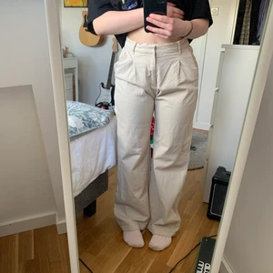 Kostymbyxor beige från Mango stl. 36 - Ett par riktigt sköna och tjusiga byxor från Mango köpta inför min konfirmation, efter den användes de aldrig mer! De är i en sand-aktig färg. Skicket är suveränt och materialet är mjukt och skönt. Jag är 165 cm lång och de är ganska långa i passformen vilket man kan tycka är snyggt! Annars skulle jag tro att de passar längre superbra! De har två olika knäppen i midjan vilket jag tycker är super!! Passar perfekt i midjan och ger en lite baggy passform i benen🥰🥰