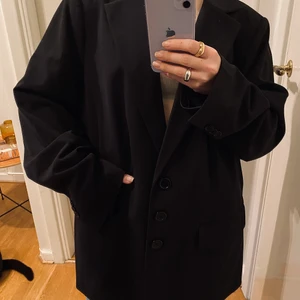 Oversized svart kavaj / blazer - Jag har rensat bland mina kavajer och behöver därför sälja denna pärla vidare!   Kavajen är sparsamt använd, fint skick och inget att anmärka på. Den kommer från Lindex och är i strl 54. Som referens är jag 160 cm lång och är en XS/S i storlek. Som ni ser bär jag kavajen oversized och får enkelt under en tjocktröja.   Passformen är rak, med ett litet sprungit baktill och med fina detaljer/knappar.   Materialet är 63% polyester, 32% viskos och 5% elastan.   Om priset är för dyrt, testa pruta! 😊