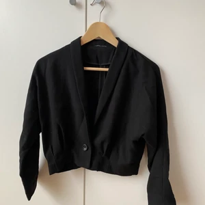 Blazer/kofta från Monki - Fin svart kortare blazer från Monki. Storlekslapp saknas men uppskattas till en S. Material enligt bild. Något skrynklig men i övrigt i fint skick.