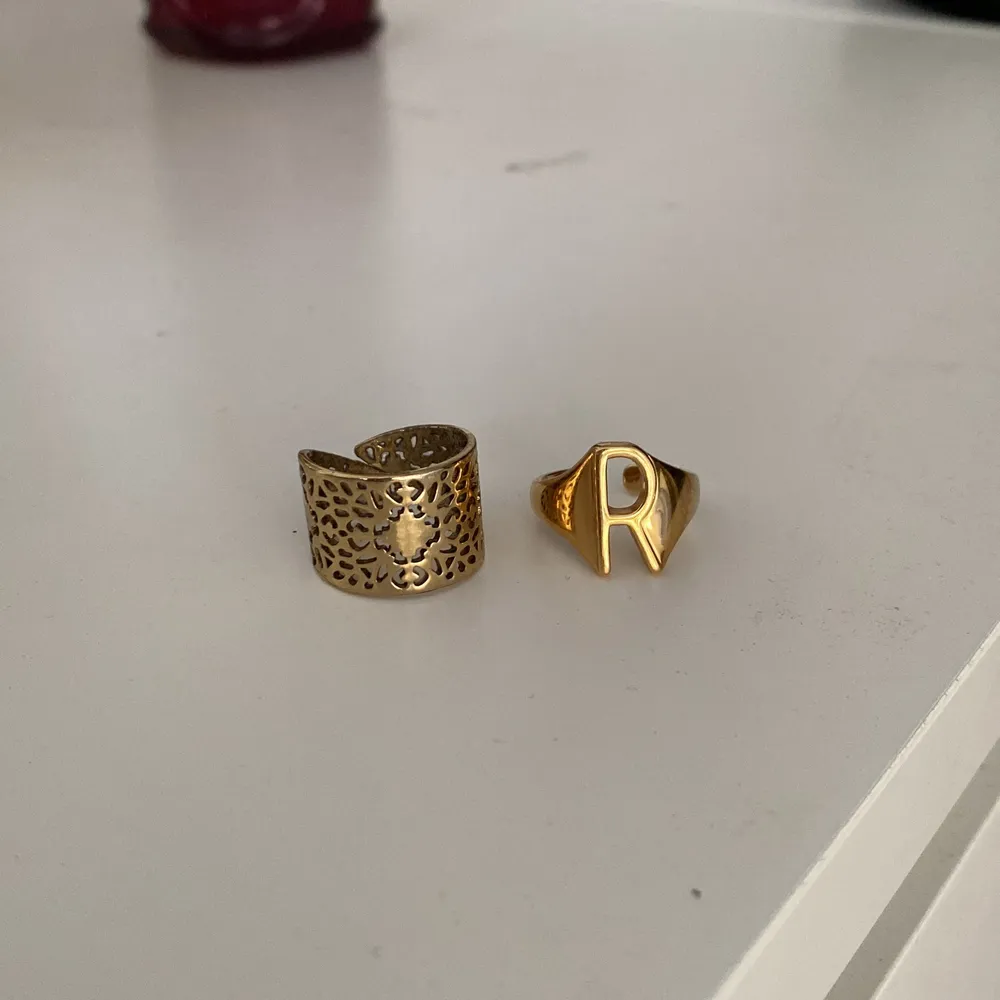 Säljer dessa ringar, den stora från pilgrim och den med ett R från safira. Båda är guldpläterade och justerbara. Säljer för 100kr styck eller båda för 150kr💛. Accessoarer.