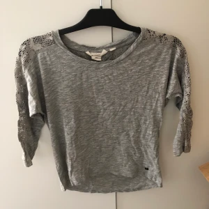Grå tröja med spetsdetaljer - Superfin grå tröja med spetsdetaljer och trekvartsärmar. I väldigt fint skick