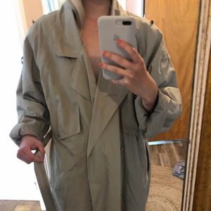Trenchcoat  - Vintage begie lång trenchcoat. Ca 10cm ovanför ankeln på mig som är 167 cm. Trenchcoat har en overzise look med fina detaljer både fram och baktill, jätte fina knappar, fickor och bälte som medför för önskad look. Uppskattas till en size M