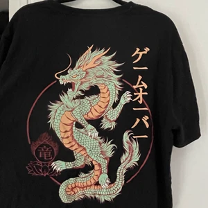 T-shirt med tryck - säljer denna suuupercoola T-shirten med stort tryck på ryggen och litet tryck på bröstet. Aldrig använt. Storlek L men liten i storleken, därför jag säljer den🐉❤️ KAN MÖTAS UPP I VÄSTERÅS ANNARS STÅR KÖPAREN FÖR FRAKTEN‼️