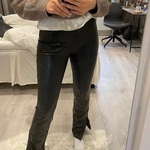 Svarta skinnbyxor - Säljer mina svarta byxor i skinnimitation med slits från Nelly! Storlek xs, sitter bra på mig som är 176 (något korta i längden), köparen står för frakten🥰🥰