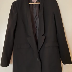 Svart kavaj H&M storlek 38 - Oversize- kavaj i svart från H&M i storlek 38. En knapp, två fickor, axelvaddar. Köpte den från Tradera men den var tyvärr för stor för mig så säljer den vidare. Frakt ingår ej. 