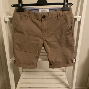 Lindex -regular shorts - Ett par beigea short från Lindex. Stretchiga short i jeans/kostymaktigt material. Storlek 140