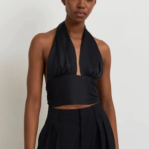 Svart halterneck topp - Svart halterneck topp som knyts både i nacken & ryggen! Storlek 32, köpt från Ginatricot! Aldrig använd endast provad! Frakt ingår i pris!