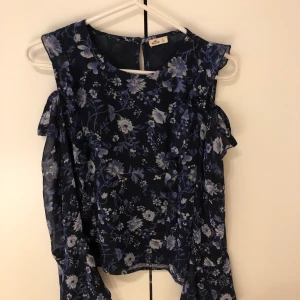 Blommig blus från Hollister - En blå blommig blus från Hollister. Den är endast använd 2 ggr så den är i väldigt bra skick. Den har ett knappspänne bak.💕💕