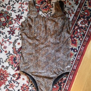 Vintage baddräkt i leopardmönster 😍 - Märkt storlek 12. Uppskattar till Large. Ev kan Medium ha? Svårt med badkläder. Hög i ryggen. Fint skick!!! Har vadderade kupor, inte tjock vaddering men lite grann.  Längd 69cm. Bredd 38cm. Benhål typ 53cm ish? Såklart jättestretchig som badkläder ju är.