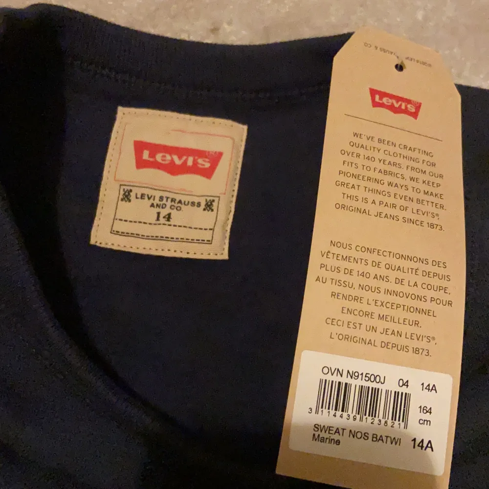 Säljer en Levi’s tröja då den aldrig har kommit till användning, helt ny med lapparna kvar. Marin blå med rött tryck.. Tröjor & Koftor.