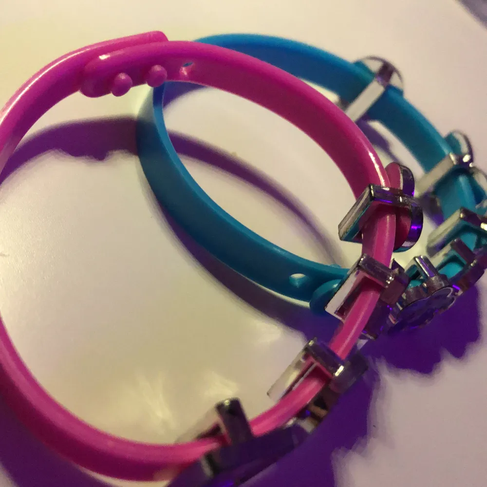 Två armband ett blått och ett rosa tillsammans 9 detaljer på armbanden som man kan ta av. Man kan ändra 3 stycken steg på armbanden så det blir olika storlekar på dom.. Accessoarer.