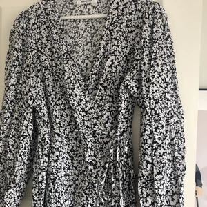 Klänning från glamorous i storlek 40 - En fin omlottklänning med ballongärmar och ett fint blommönster från Glamorous i storlek 40 men passar en med storlek 36-38. Jättefin nu i sommar och använd fåtal gånger. Köparen står för frakten. 