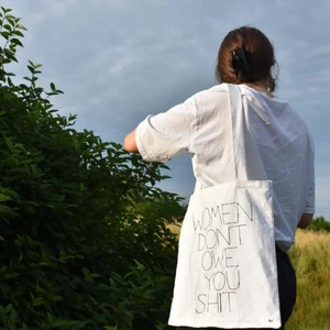 Tote bag med motiv - Tote bag gjort på secondhand tyg med citatet "women don't owe you shit". Den är 34 cm på breden och 39 cm på längden