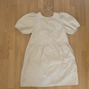 Gullig klänning - Supersöt klänning från hm, beige-vit i ett lite skimrigt material. Knytning bak och öppen rygg. Storlek m men passar även mig fint som brukar ha s. Skriv för fler bilder🥰