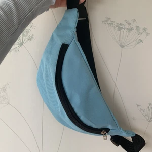 Ljusblå magväska - Jättesnygg ljusblå magväska / fannypack/ bumbag! Asfin på sommaren! Har någon liten fläck som borde gå bort om man vill tvätta den! Jag har inte tyckt den synts så därför har inte jag gjort det! Hör av er för frågor