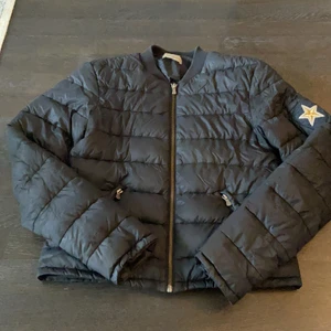 Dunjacka från Hunkydory  - Svart dunjacka från Hunkydory i stl S. Två sidofickor med dragkedja samt en stjärna på ena ärmen. Mycket bra skick!