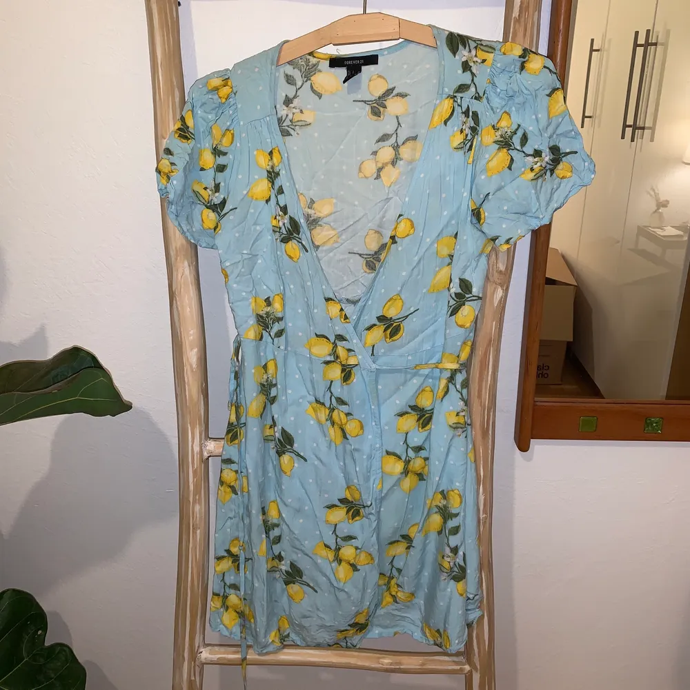 En mönstrad omlottklänning från Forever 21 i blått med citronmönster. Frakt ingår! Storlek S.. Klänningar.