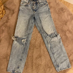 Jeans  - Blåa jeans med hål i knäna. 