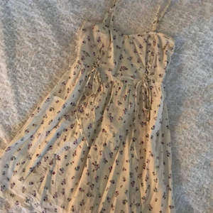 Vit blommig sommarklänning - Kort vit sommarklänning med små rosa/lila blommor. Smala axelband.