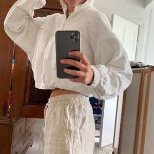 Vit sweater - Vit croppad sweater med resår i muddarna och en dragkedja i kragen.