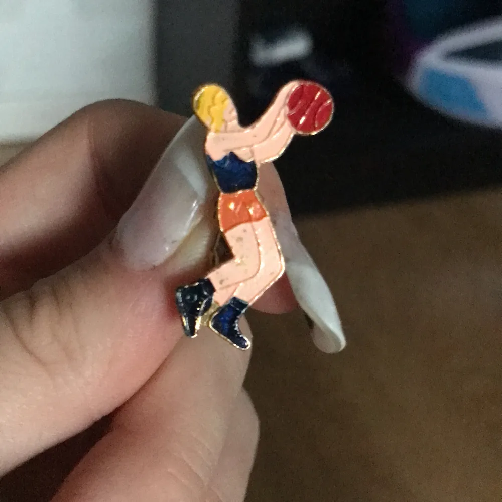 En liten pin som är formad som en kunde som spelar basket . Accessoarer.