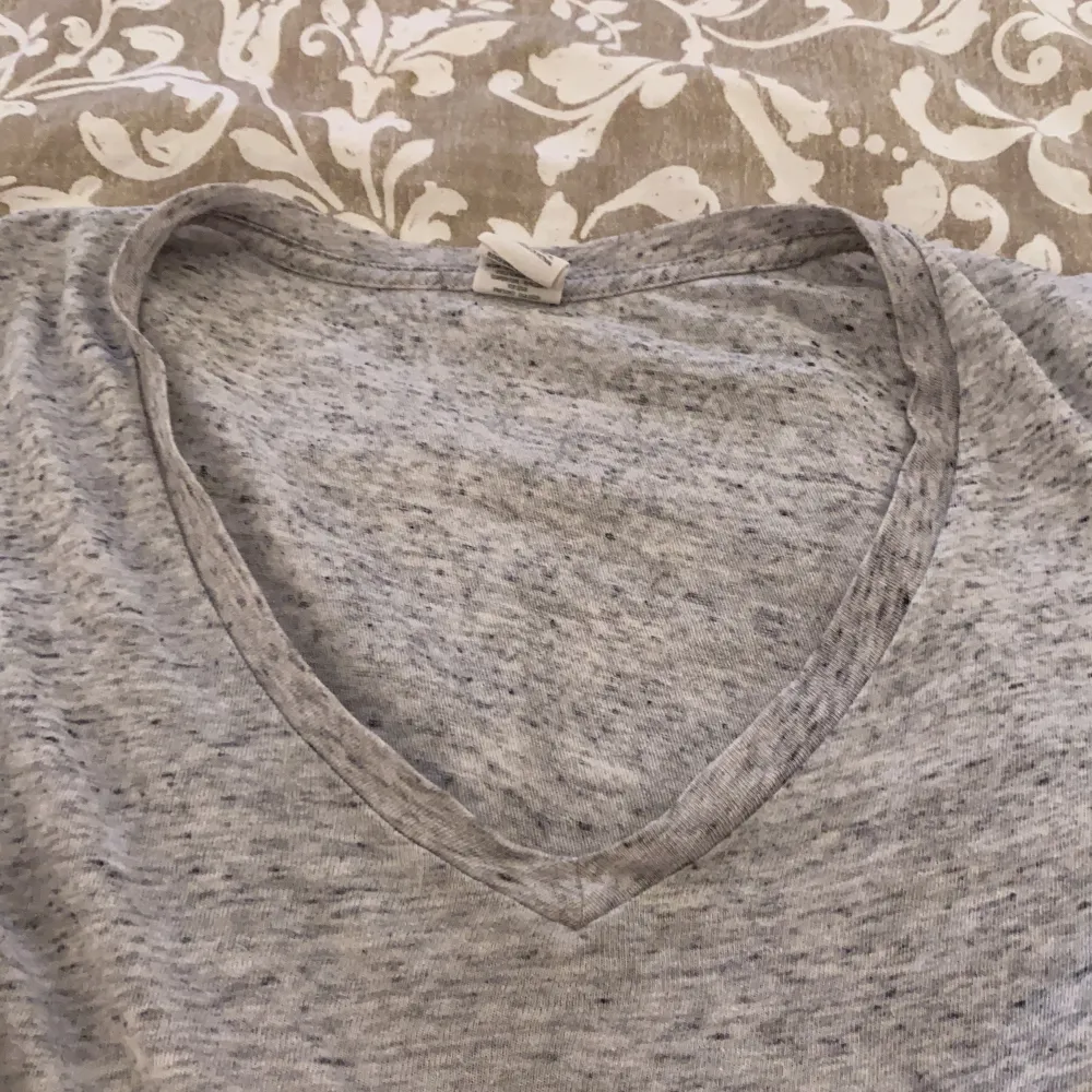 En grå t-shirt med v-ringning, xs men väldigt stor i storlek . T-shirts.