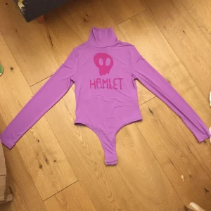 Lila polotröja och body strl M från NA-KD - En lila polotröja och body. Använd endast en gång. Trycket är målat för hand av mig och kommer från Tv serien Trollhunters (trolljakten). Kommer från  NA-KD. Frakt ingår ej
