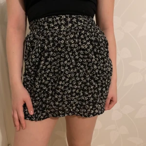 Blommig kjol - Svart blommig kjol med fickor, aldrig använt:) väldigt stretchig:) 50kr+frakt