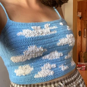 Virkad topp Blå himmel med moln - Topp med himmelsmotiv som jag har virkat själv. Passar S-L eftersom den går att snöra på olika sätt. Visas på en M. Akryl- och bomullsgarn, det vita garnet ger en 3D-effekt. Den blåa färgen liknar mest den på bild 1 i verkligheten. Kolla gärna in mitt konto för fler virkade toppar! 😊☁️🐳