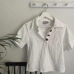 Vit blus med dekorativa knappar Stl34  - En vit kortärmad blus från ASOS med dekorativa knappar i stl 34. Blusen är nästintill ny. Köpt för 439kr. 