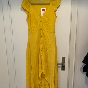 Aldrig använd gul sommarklänning - Väldigt fin gul sommarklänning med knappar på framsidan. Klänningen är längre bak och faller fint. Aldrig använd med prislapp på då storleken var fel. Stl S men liten i storleken