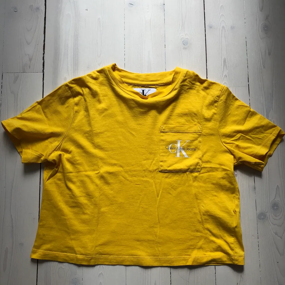 En gul Calvin Klein T-shirt i en kort modell.     Storleken S. . T-shirts.
