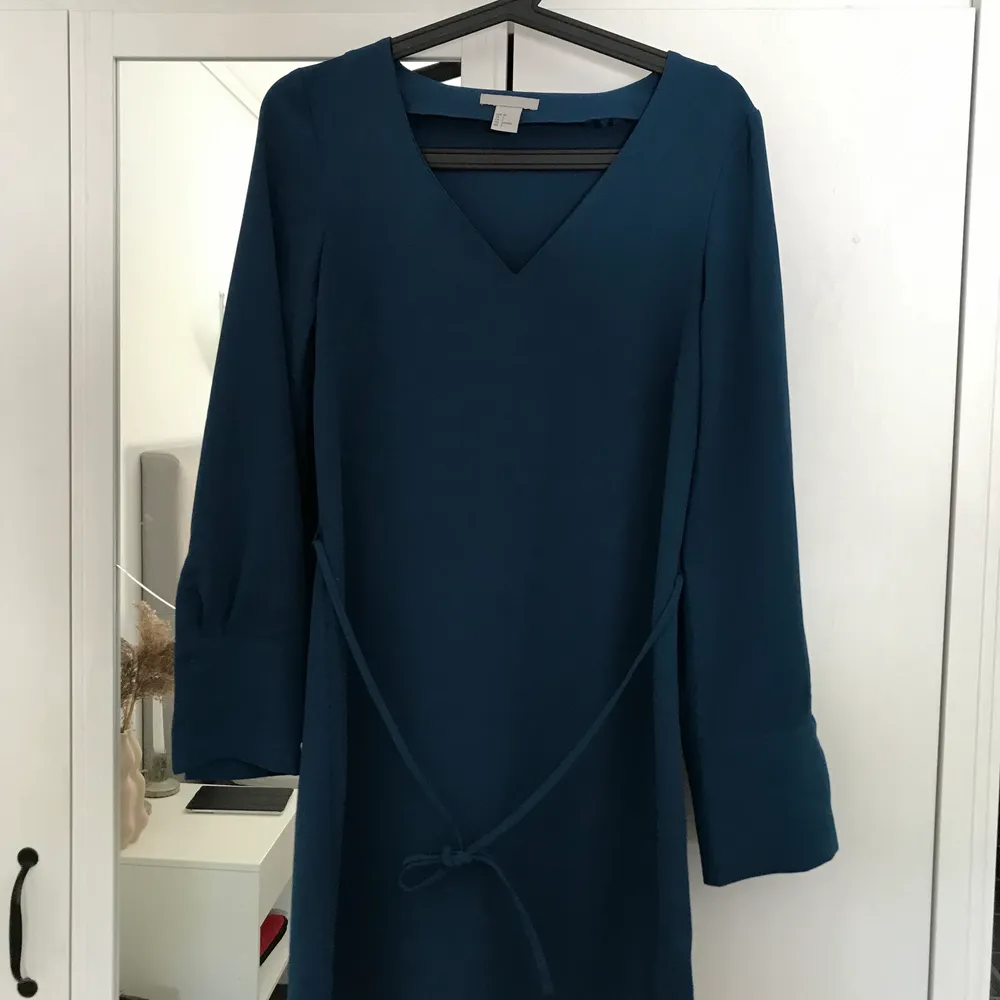 Jättefin mörkblå klänning från H&M. V- ringad, knyte runt magen och knappar vid ärmslutet. Nästintill oanvänd, priset kan diskuteras. Köparen står för frakten. . Klänningar.