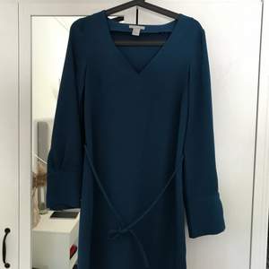 Jättefin mörkblå klänning från H&M. V- ringad, knyte runt magen och knappar vid ärmslutet. Nästintill oanvänd, priset kan diskuteras. Köparen står för frakten. 
