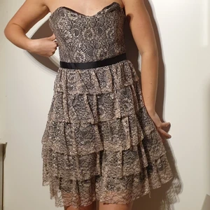 Volangklänning, storlek L  - Beige, brun, svart kort volangklänning. Lite större över bysten med tajt kedja kring midjan, passar storlek M också. Polyester. I gott skick. 