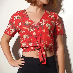 Vero Moda topp, storlek M, oanvönd  - Oanvänd. Röd och vitblommig magtopp som knyts över magen, längd 45 cm. Material: Viskos. Frakt tillkommer på 48-51 kr ❣  