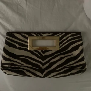 Michael kors väska - Superfin Michaelkors-clutch i zebramönster med gulddetaljer. Endast använd på min studentbal så i princip nytt skick. Köpt från en tjej begagnat som inte hade fått användning för den. Kostade 600 nypris. Om fler är intresserade så blir det budgivning:)