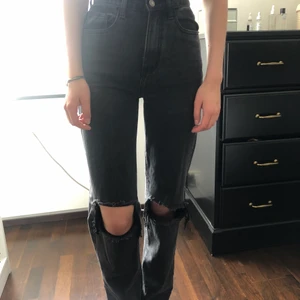 Prettylittlething jeans i storlek 34 - Mörkgrå jeans med slitningar vid knäna i nytt skick, har endast använt byxorna 2 gånger. Är 176 cm lång och byxorna når ner till golvet på mig!!