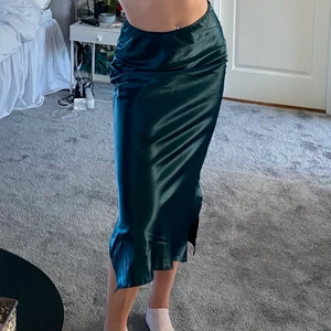 Sidenkjol - I en mörkgrön korallfärg. Köparen står för frakt, möts även i Stockholm C/Enskede. Passar mig som har S och är 172