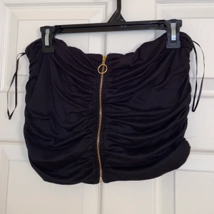 Kort svart tub topp med dragkedja - Oanvänd tuptopp med guld dragkedja från fashionnova, mjukt material, liten i storleken